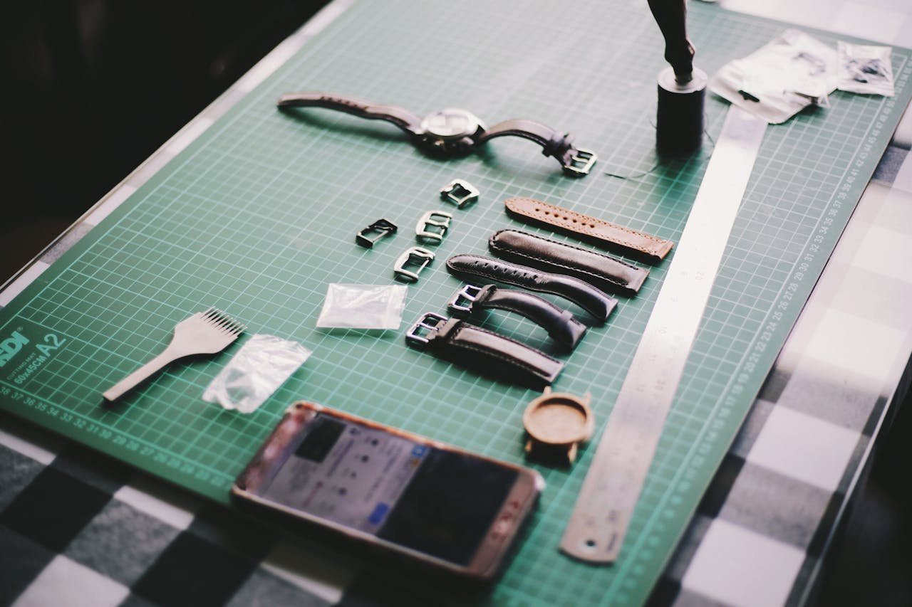 our-services-2 Close-up of watchmaking tools and leather straps on a crafting table.